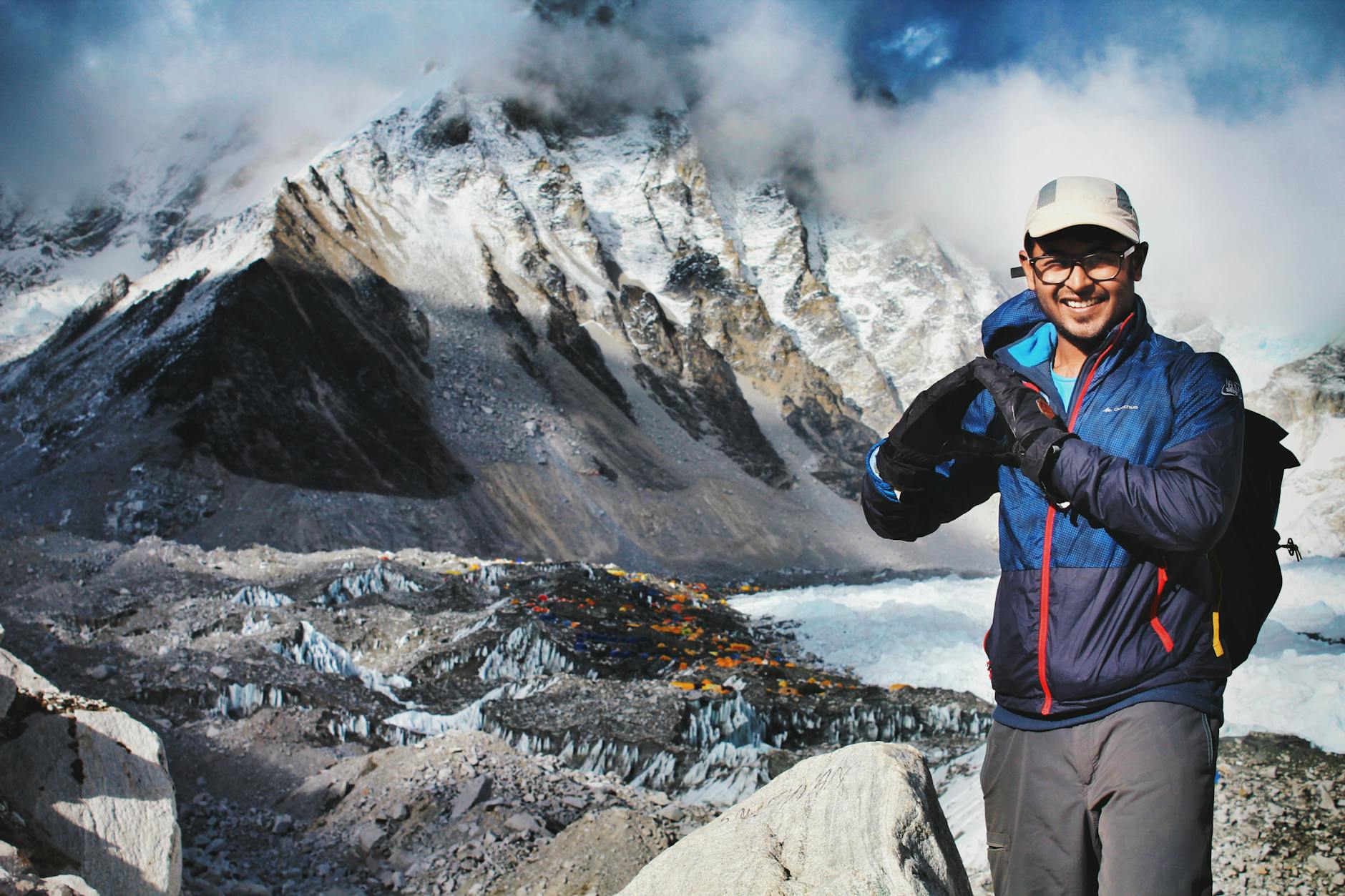 a man in blue jacket standing near the snow covered mountain